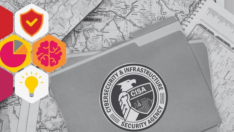 a manila folder rests on top of a stack of road maps. The folder bears the CISA logo
