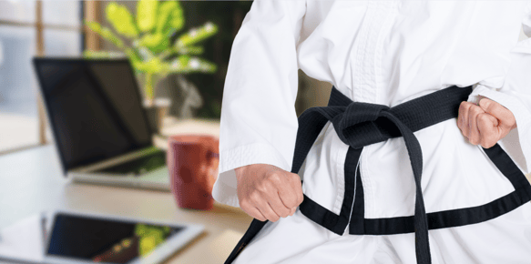 a person in a karate uniform takes a defensive stance in front of a computer