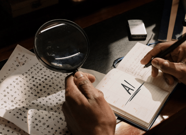 A hand holding a magnifying glass looking at characters, having written "AI" in a notebook