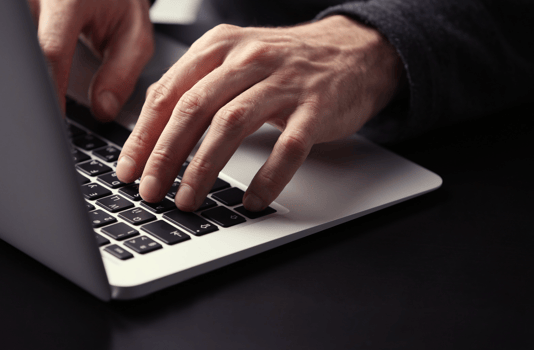 Hands typing on a computer