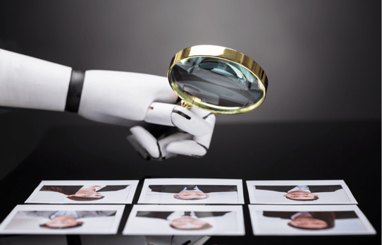 a robotic hand holds a magnifying glass and examines headshots of humans