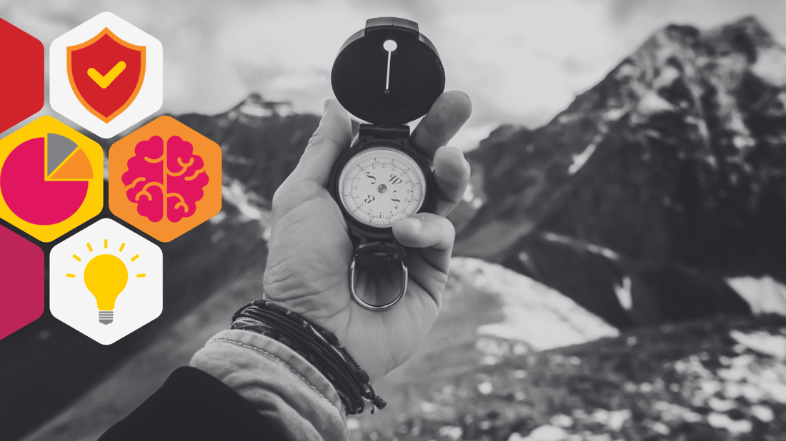 Hand holding a compass in front of a mountainous background